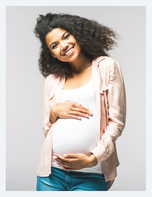 A Pregnant woman smiling, holding her belly